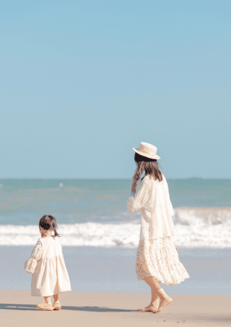 Mère et sa fille au bord de la plage en tenue blanche